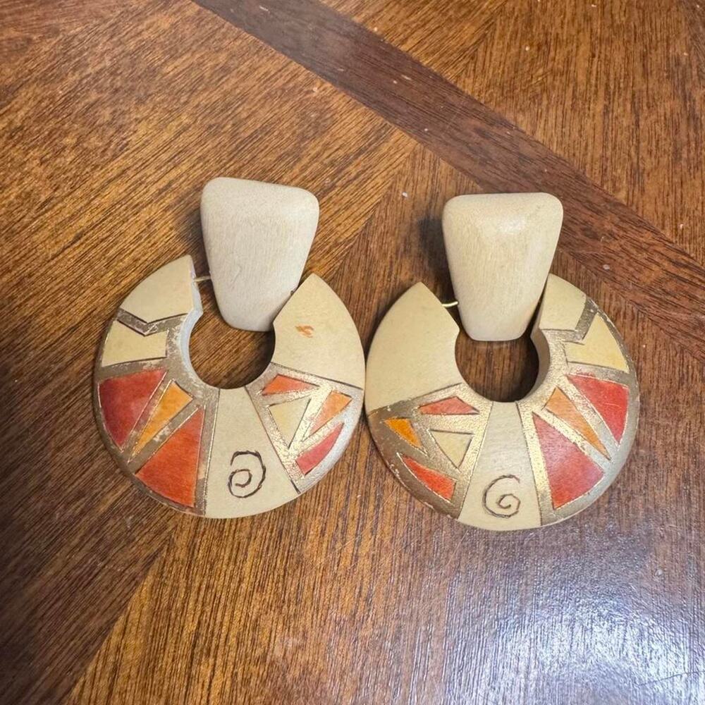 Wooden earrings with design featuring orange, red, and beige triangles & swirls